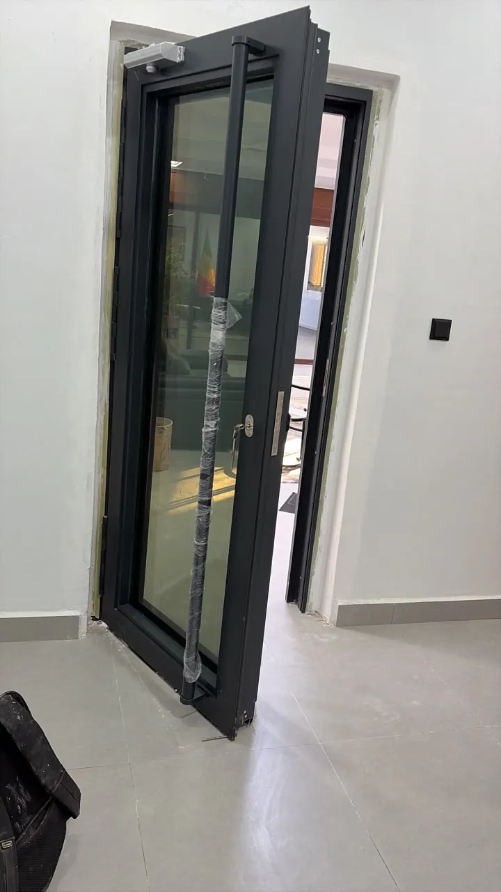 Glazed security door standing open during installation, pull handle still in protective film